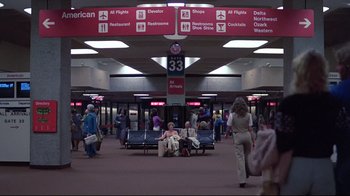 Movie still from “El Norte” (1983), directed by Gregory Nava – A couple of people sitting on a bench in an airport; Extreme Wide shot, High angle