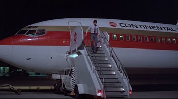 Movie still from “El Norte” (1983), directed by Gregory Nava – A man standing on the stairs of an airplane at night; Wide shot, Low angle