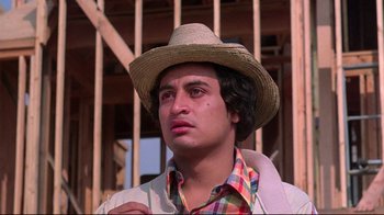 Movie still from “El Norte” (1983), directed by Gregory Nava – A man wearing a straw hat in front of a wooden structure; Close Up shot, Low angle
