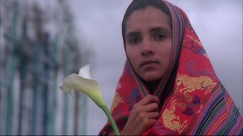 Movie still from “El Norte” (1983), directed by Gregory Nava – A woman wrapped in a blanket holding a flower; Close Up shot, Low angle