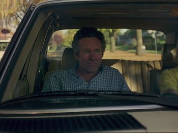 Movie still from “Elephant” (2003), directed by Gus Van Sant – A man sitting in the back seat of a car; Medium shot, Over the shoulder angle