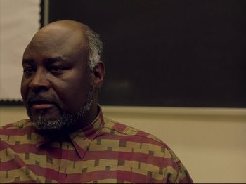 Movie still from “Elephant” (2003), directed by Gus Van Sant – An older man wearing a colorful shirt is looking to his left; Close Up shot, Low angle