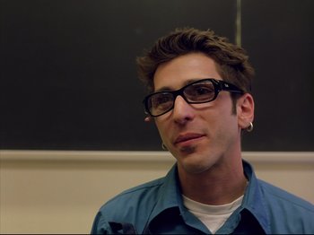 Movie still from “Elephant” (2003), directed by Gus Van Sant – A man wearing glasses and a blue shirt; Close Up shot, Low angle