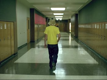 Movie still from “Elephant” (2003), directed by Gus Van Sant – A man walking down a hallway in a school; Wide shot, Low angle