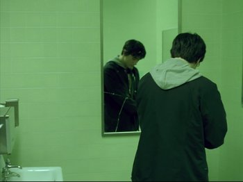 Movie still from “Elephant” (2003), directed by Gus Van Sant – A man standing in front of a mirror in a bathroom; Wide shot, High angle