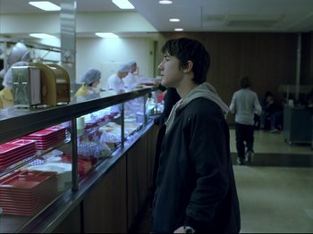 Movie still from “Elephant” (2003), directed by Gus Van Sant – A man standing in front of a counter in a restaurant; Medium shot, Over the shoulder angle