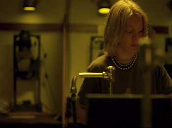 Movie still from “Elephant” (2003), directed by Gus Van Sant – A woman sitting in front of a computer monitor; Medium shot, Low angle