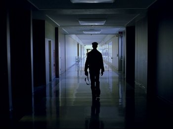 Movie still from “Elephant” (2003), directed by Gus Van Sant – A man walking down a hallway in a building; Wide shot, Low angle