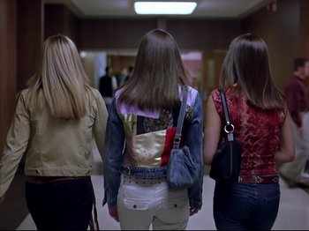 Movie still from “Elephant” (2003), directed by Gus Van Sant – Three women are standing in a hallway with their backs turned to the camera; Medium shot, Low angle