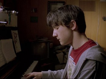 Movie still from “Elephant” (2003), directed by Gus Van Sant – A young man playing the piano in a living room; Close Up shot, Low angle