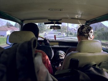 Movie still from “Elephant” (2003), directed by Gus Van Sant – A group of people riding in the back of a car; Medium shot, High angle