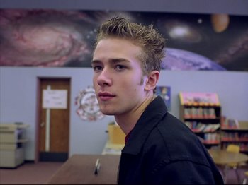 Movie still from “Elephant” (2003), directed by Gus Van Sant – A young man in a black shirt is in a library; Close Up shot, Low angle