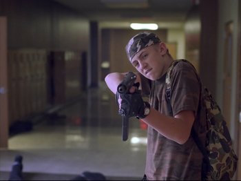Movie still from “Elephant” (2003), directed by Gus Van Sant – A young man holding a baseball bat in a hallway; Medium shot, Low angle