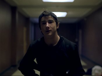 Movie still from “Elephant” (2003), directed by Gus Van Sant – A young man standing in a dark hallway; Close Up shot, Low angle