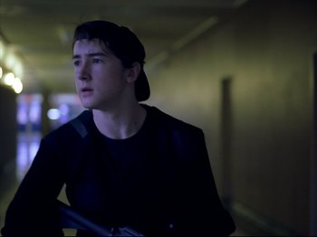 Movie still from “Elephant” (2003), directed by Gus Van Sant – A man in a black shirt holding a gun; Medium shot, Over the shoulder angle