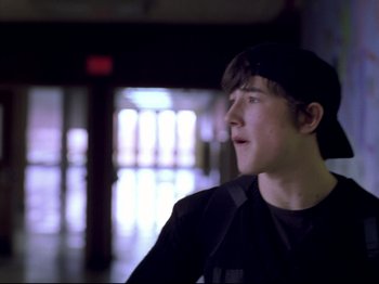 Movie still from “Elephant” (2003), directed by Gus Van Sant – A young man wearing a black hat and a black jacket; Close Up shot, Over the shoulder angle