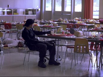 Movie still from “Elephant” (2003), directed by Gus Van Sant – A man sitting at a table in front of a plate of food; Wide shot, High angle