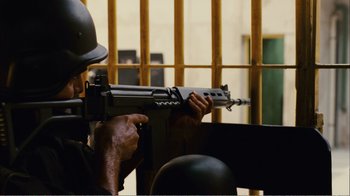 Movie still from “Elite Squad 2: The Enemy Within” (2010), directed by José Padilha – A man holding a rifle in front of a jail cell; Medium shot, High angle