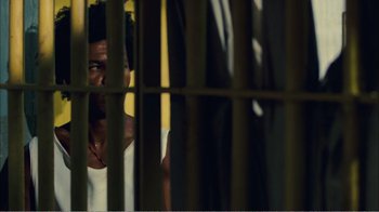 Movie still from “Elite Squad 2: The Enemy Within” (2010), directed by José Padilha – A man looking through bars of a jail cell; Close Up shot, Over the shoulder angle