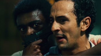 Movie still from “Elite Squad 2: The Enemy Within” (2010), directed by José Padilha – A man holding a gun next to another man; Close Up shot, Low angle