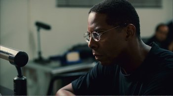 Movie still from “Elite Squad 2: The Enemy Within” (2010), directed by José Padilha – A person wearing glasses and a black shirt; Close Up shot, Over the shoulder angle