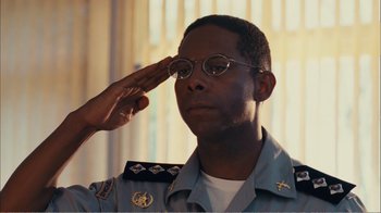 Movie still from “Elite Squad 2: The Enemy Within” (2010), directed by José Padilha – A man saluting while wearing glasses and a uniform; Close Up shot, Low angle