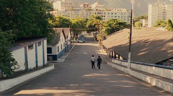Movie still from “Elite Squad 2: The Enemy Within” (2010), directed by José Padilha – Two people walking down a street with a building in the background; Extreme Wide shot, High angle