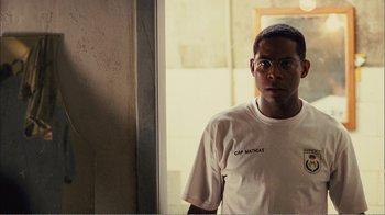 Movie still from “Elite Squad 2: The Enemy Within” (2010), directed by José Padilha – A man wearing glasses and a t - shirt standing in front of a mirror; Close Up shot, Over the shoulder angle