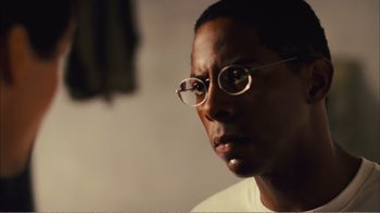 Movie still from “Elite Squad 2: The Enemy Within” (2010), directed by José Padilha – A person wearing glasses and a white shirt; Close Up shot, Low angle