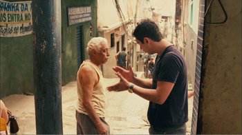 Movie still from “Elite Squad 2: The Enemy Within” (2010), directed by José Padilha – A man talking to an older man on the street; Medium shot, Over the shoulder angle
