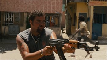 Movie still from “Elite Squad 2: The Enemy Within” (2010), directed by José Padilha – A man holding an ak - 4 7 in his hands; Medium shot, Low angle