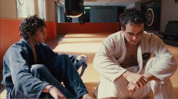 Movie still from “Elite Squad 2: The Enemy Within” (2010), directed by José Padilha – Two men sitting on the ground in a room; Medium shot, Low angle