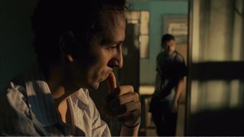 Movie still from “Elite Squad 2: The Enemy Within” (2010), directed by José Padilha – A man is sitting in a room with his finger in his mouth; Close Up shot, Over the shoulder angle