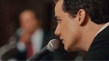 Movie still from “Elite Squad 2: The Enemy Within” (2010), directed by José Padilha – A person holding a microphone; Close Up shot, Over the shoulder angle