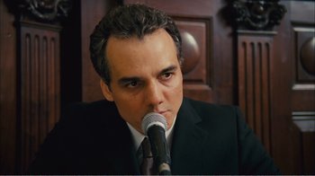 Movie still from “Elite Squad 2: The Enemy Within” (2010), directed by José Padilha – A person wearing a suit holding a microphone; Close Up shot, Over the shoulder angle