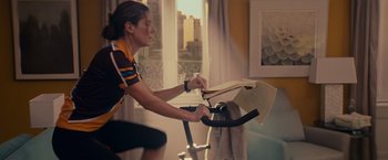 Movie still from “The Proposal” (2009), directed by Anne Fletcher – A person on an exercise bike in front of a window; Medium shot, Over the shoulder angle