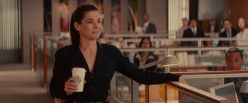 Movie still from “The Proposal” (2009), directed by Anne Fletcher – A woman holding a starbucks coffee cup in a cafe; Medium shot, Over the shoulder angle