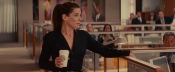 Movie still from “The Proposal” (2009), directed by Anne Fletcher – A woman holding a starbucks coffee cup in a cafe; Medium shot, Over the shoulder angle