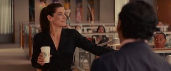 Movie still from “The Proposal” (2009), directed by Anne Fletcher – A woman in a black shirt is talking to a man in a black suit; Medium shot, Over the shoulder angle