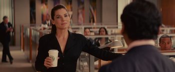 Movie still from “The Proposal” (2009), directed by Anne Fletcher – A woman holding a cup of coffee in her hand; Medium shot, Over the shoulder angle