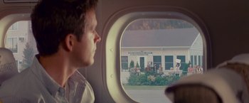 Movie still from “The Proposal” (2009), directed by Anne Fletcher – A man looking out of an airplane window at people; Wide shot, Over the shoulder angle