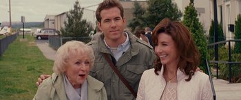 Movie still from “The Proposal” (2009), directed by Anne Fletcher – Two women and a man standing next to each other; Medium shot, Over the shoulder angle