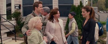 Movie still from “The Proposal” (2009), directed by Anne Fletcher – A group of people standing next to each other on the sidewalk; Medium shot, Over the shoulder angle