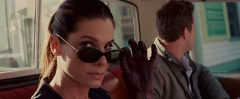 Movie still from “The Proposal” (2009), directed by Anne Fletcher – A woman wearing sunglasses while holding her hand up to her face; Close Up shot, Over the shoulder angle