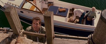 Movie still from “The Proposal” (2009), directed by Anne Fletcher – A man sitting on a dock next to a boat in the water; Medium shot, Over the shoulder angle