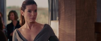 Movie still from “The Proposal” (2009), directed by Anne Fletcher – A beautiful woman in a gray top looking at the camera; Close Up shot, Over the shoulder angle