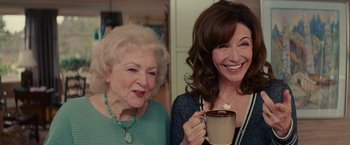 Movie still from “The Proposal” (2009), directed by Anne Fletcher – Two women are smiling while holding a cup of hot chocolate; Medium shot, High angle