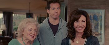 Movie still from “The Proposal” (2009), directed by Anne Fletcher – Two women and a man standing next to each other; Close Up shot, Over the shoulder angle