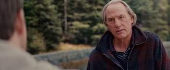 Movie still from “The Proposal” (2009), directed by Anne Fletcher – An older man in a wooded area looking at the camera; Close Up shot, Over the shoulder angle