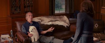 Movie still from “The Proposal” (2009), directed by Anne Fletcher – An older man sitting on a couch holding a white dog; Medium shot, Over the shoulder angle